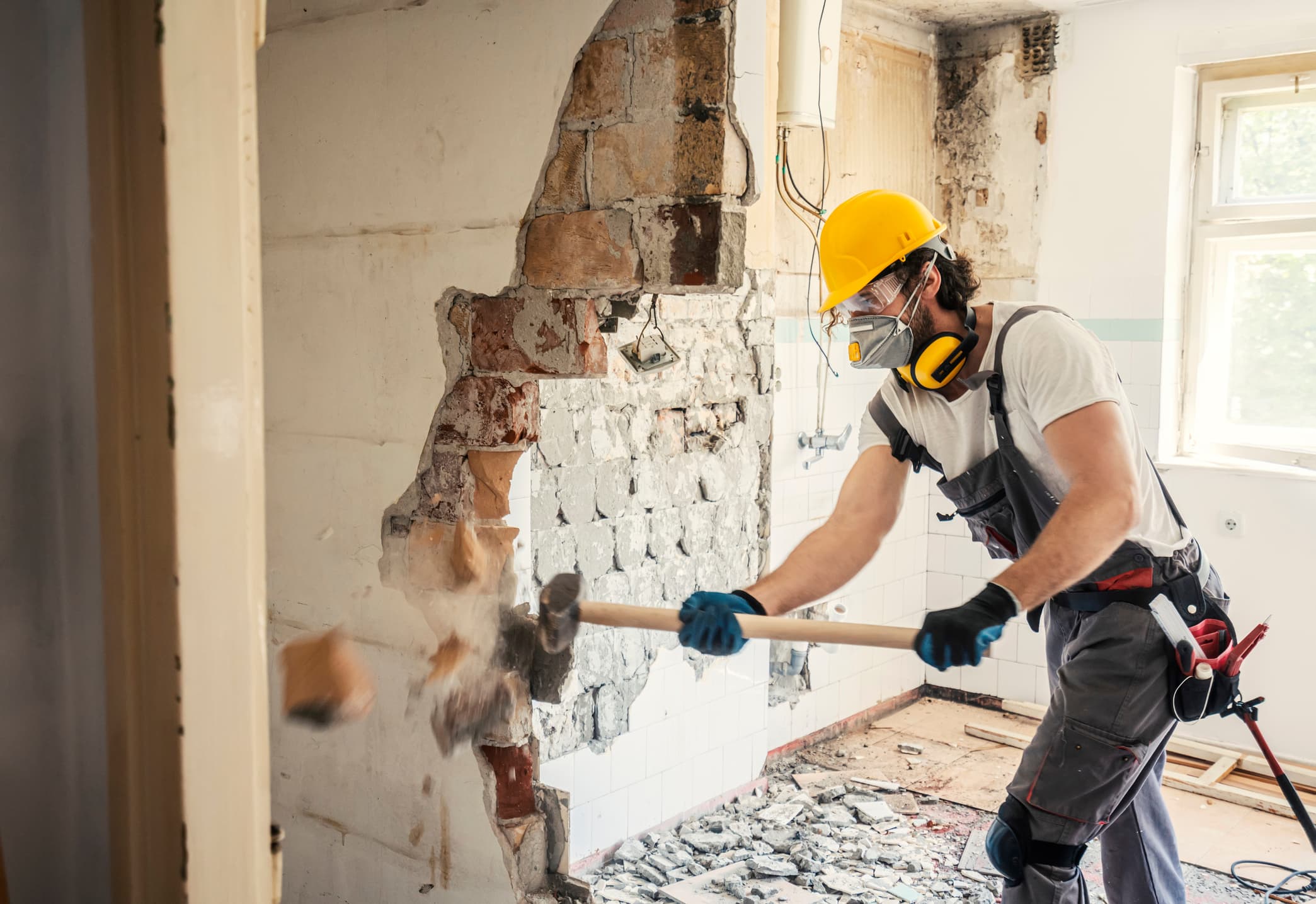 Worker using hammer to demo a wall 