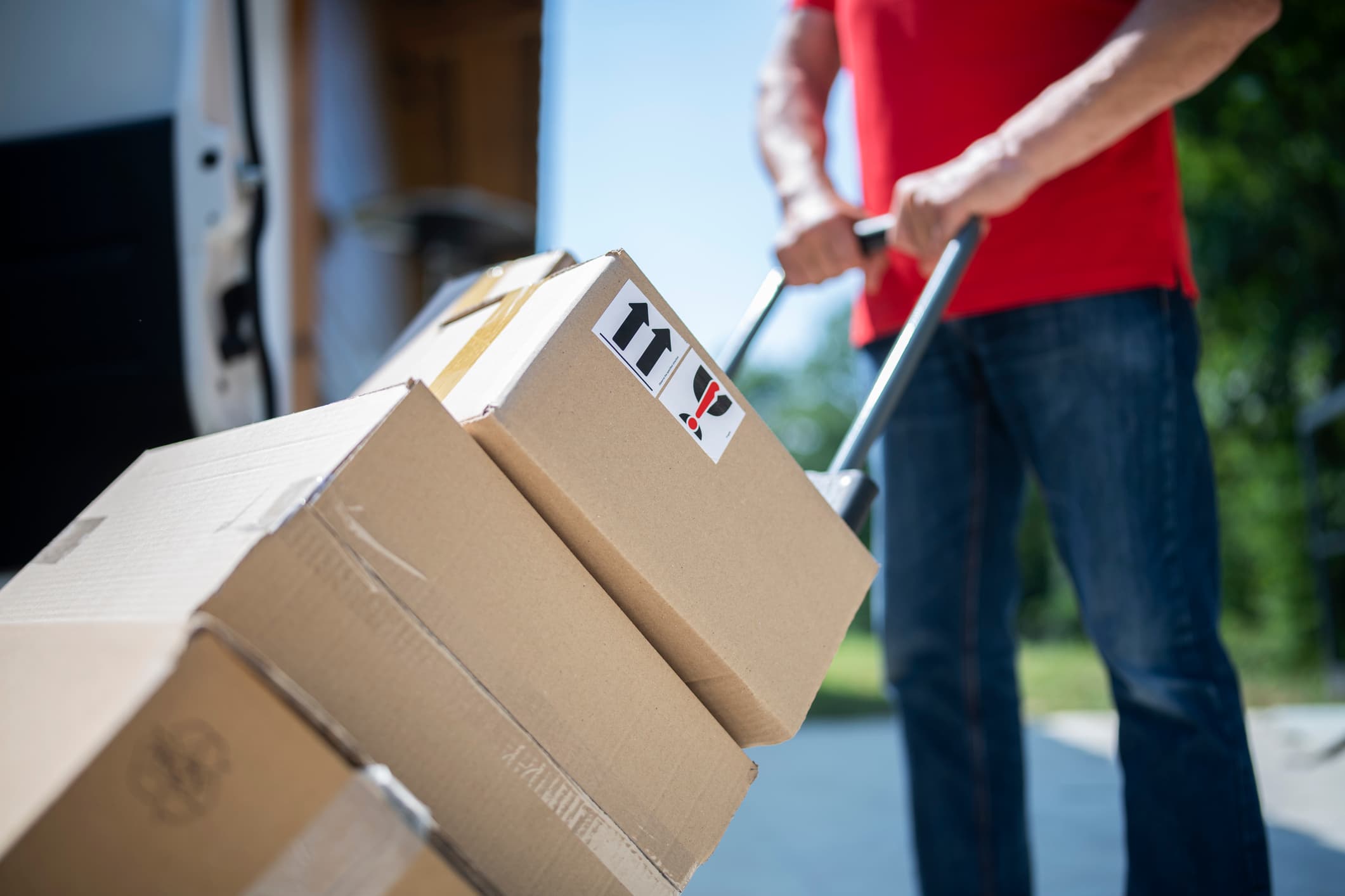 Shot of unrecognizable delivery guy pushing cart full of parcels. stock photo