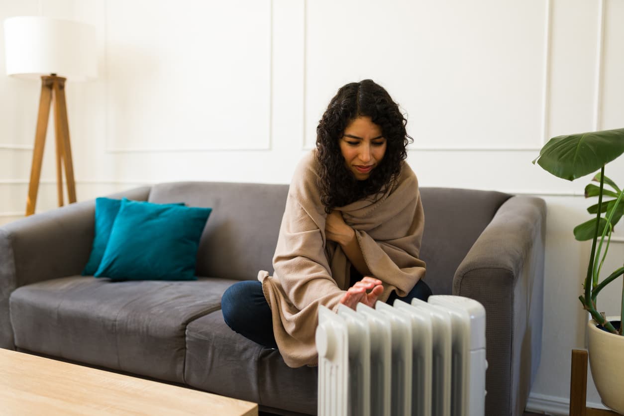 young woman using space heater to supplement apartment heat